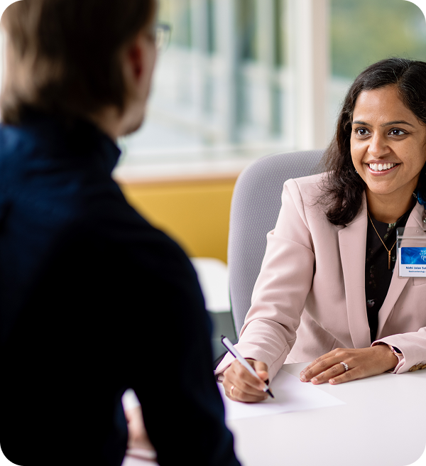 Mayo Clinic physician smiling and speaking with a patient across a desk during a consultation.