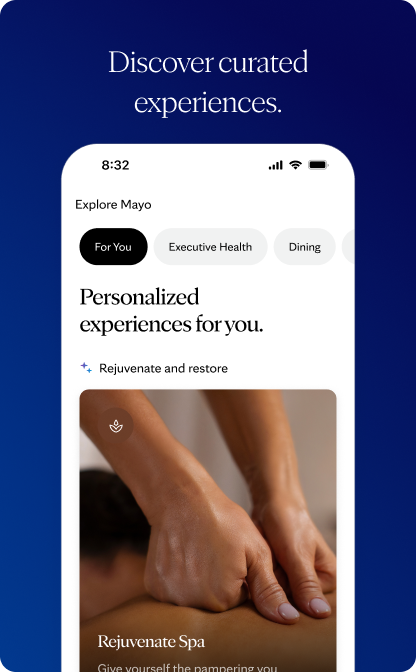 Smartphone mockup on a dark blue background displaying the Explore Mayo screen with personalized experiences and a Rejuvenate Spa card featuring a photograph of a massage. Above the phone, a heading reads “Discover curated experiences.”