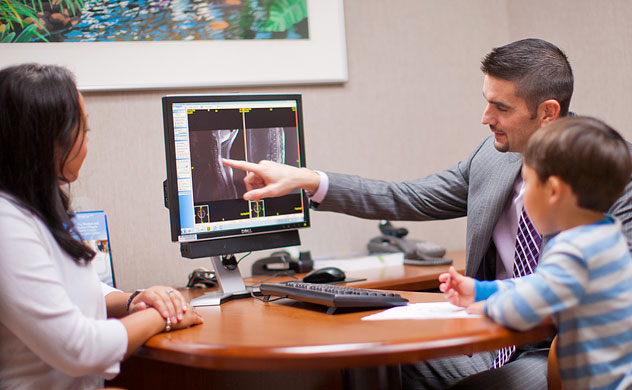 Photo of doctor showing medical images to a child and parent