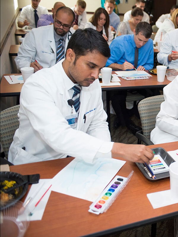 A medical student works on a watercolor.