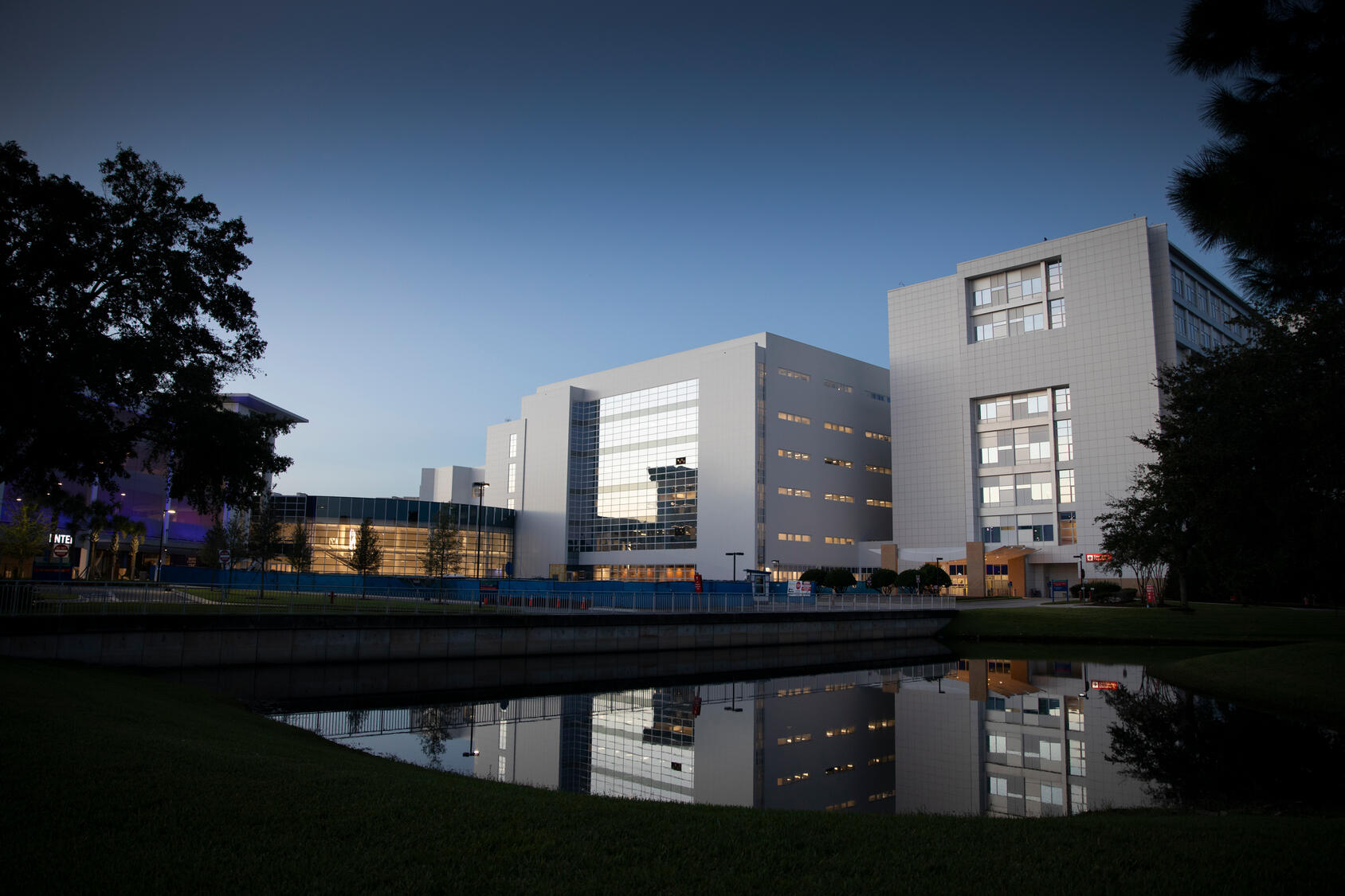 Exterior view of Mayo Clinic Florida building reflected in a calm pond at dusk.