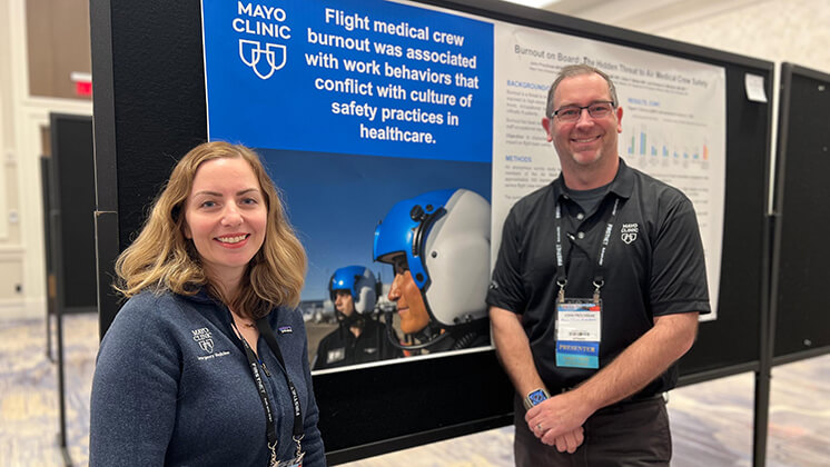 A man and a woman standing in front of a poster.