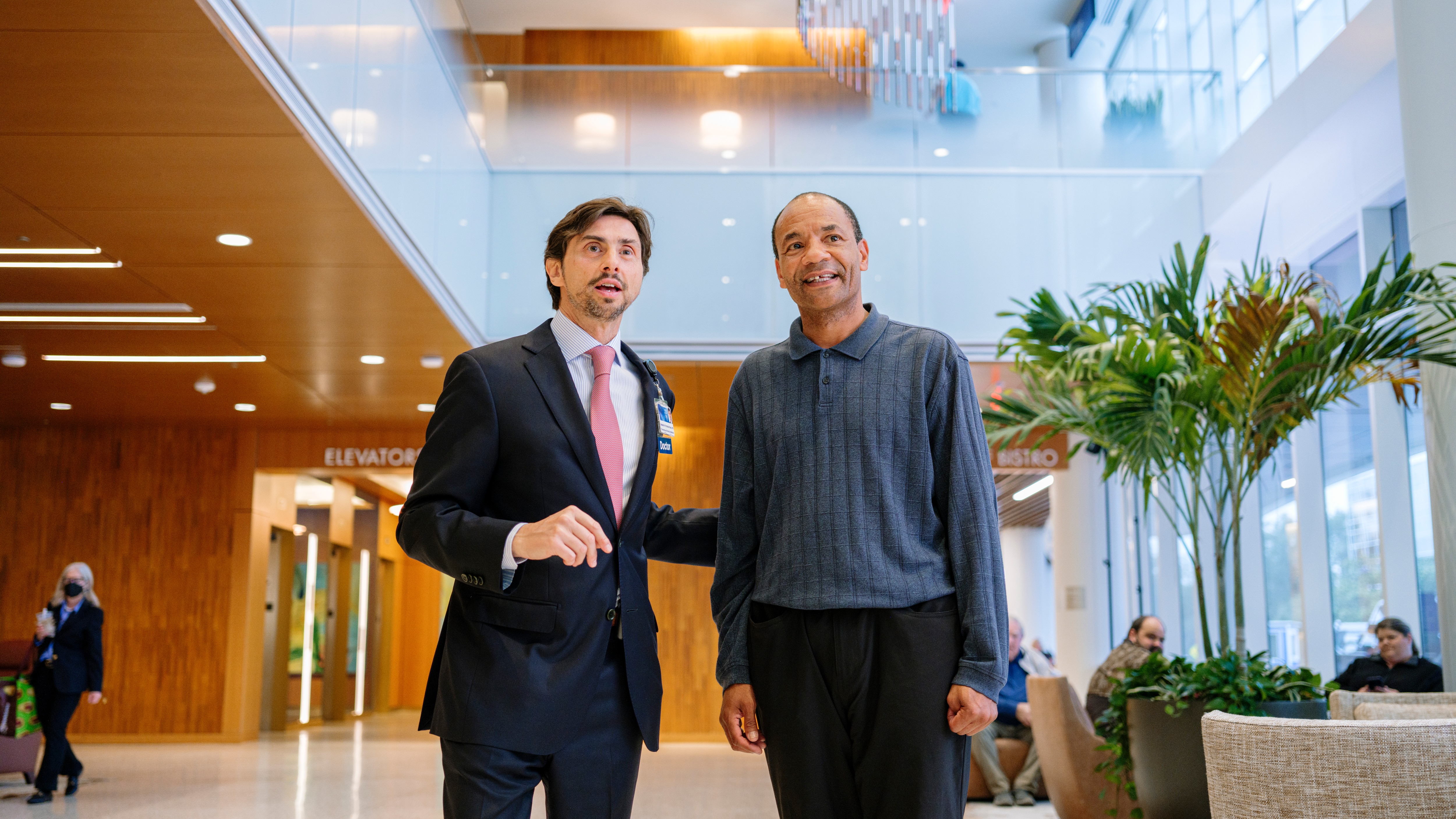 Mayo Clinic physician gestures while speaking with a patient in a clinic lobby.